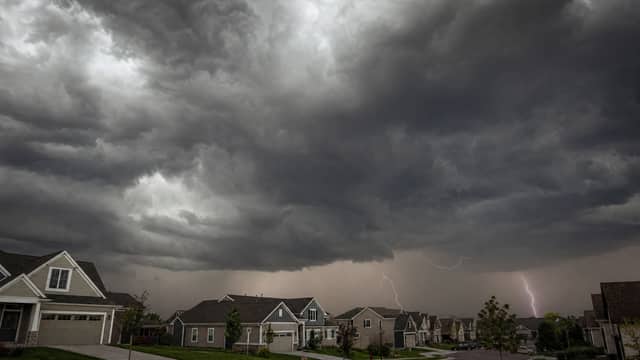 Dark storm clouds gathering over a neighborhood of shingle-roofed homes